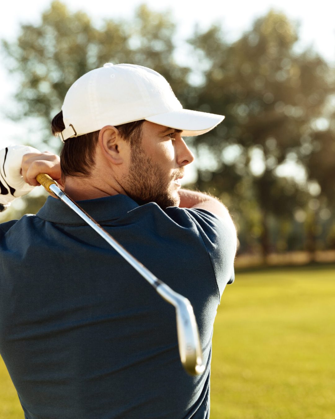Close up of a young concentrated man shooting golf ball while playing at the green course