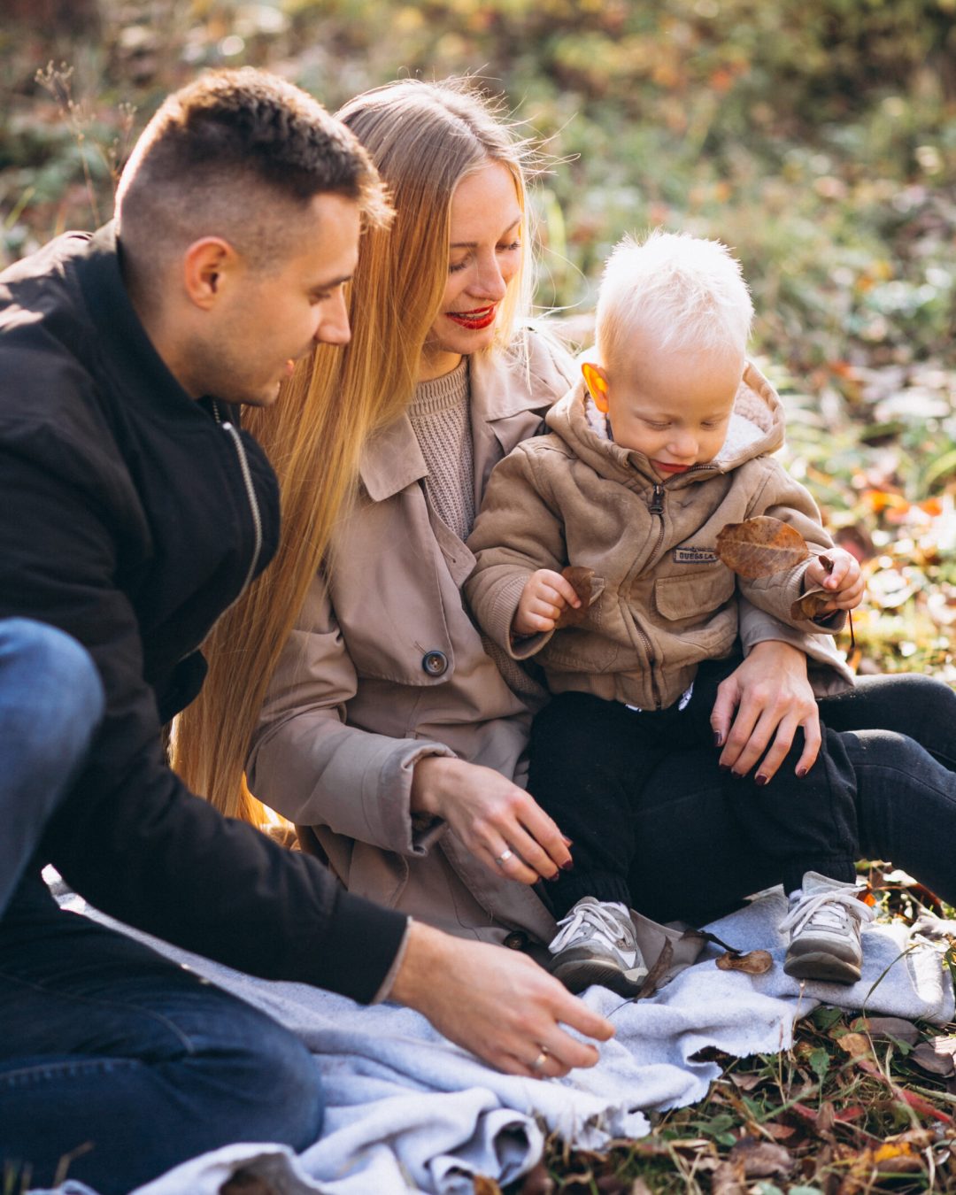 Family having small picnic with their son in autumn park